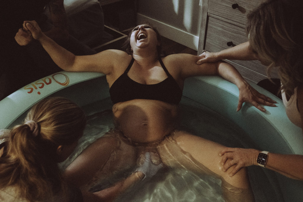 Mom powerfully yelling during "ring of fire" while midwife catches babies head during home birth in Kansas City 