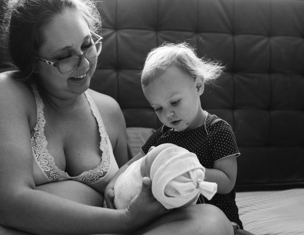 "Baby" sister gazing at the newest baby of the family after a home birth Kansas City 