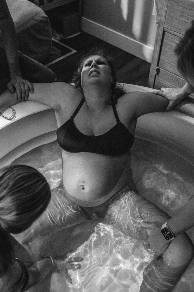 Mom grimacing during last contractions before delivering baby during home birth Kansas City 