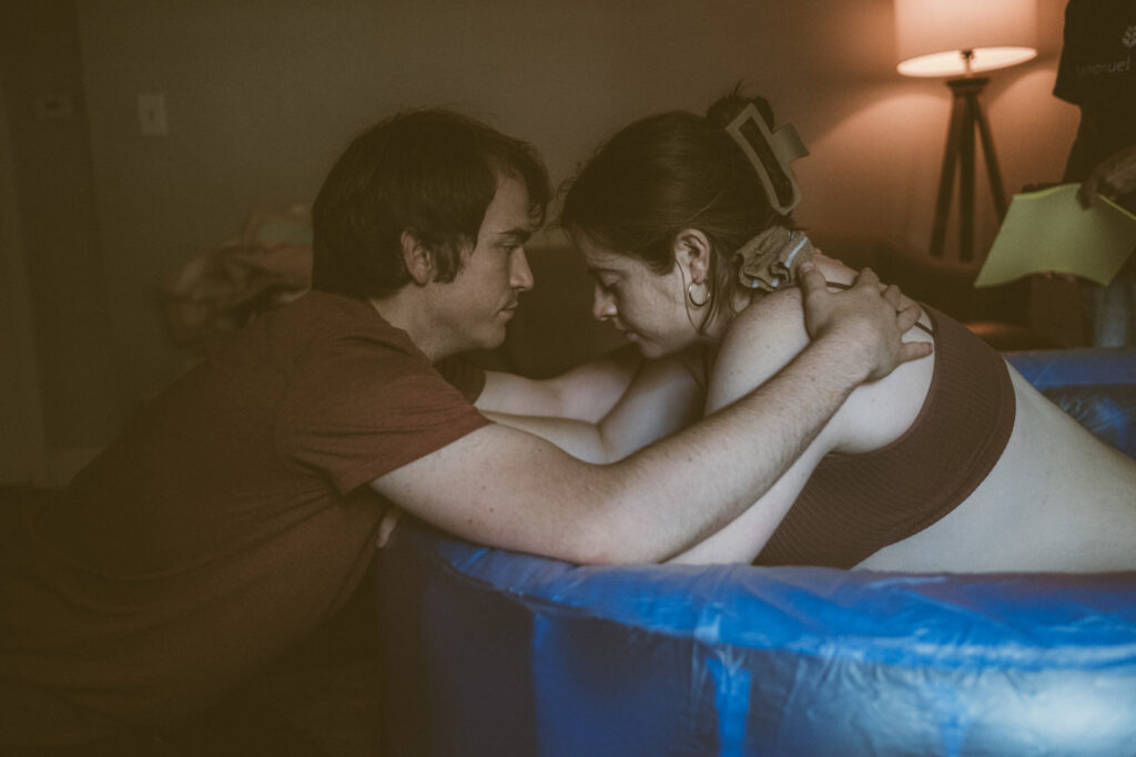 husband lovingly supporting wife during home birth of their second child in Kanas 